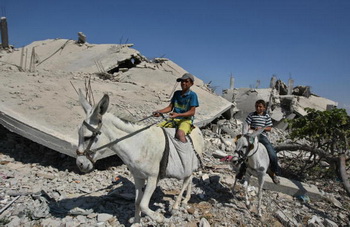 Палестинский мальчик едет к дому через развалины в Секторе Газа. Фото: MAHMUD HAMS/AFP/Getty Images