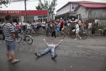 Один из родителей лежит на земле, в знак протеста против закрытия школы для детей рабочих-мигрантов в районе Хайдянь в Пекине. (фотоархив Великой Эпохи) Один из родителей лежит на земле, в знак протеста против закрытия школы для детей рабочих-мигрантов в районе Хайдянь в Пекине. (фотоархив Великой Эпохи)