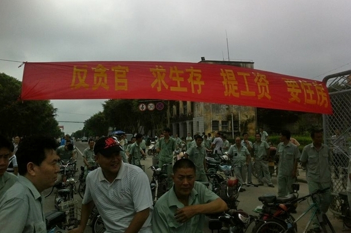Надпись на плакате: «Против коррупции, хотим условий для жизни, повышения зарплаты, жильё». Забастовка рабочих. Провинция Гуандун. Май 2013 года. Фото с epochtimes.com