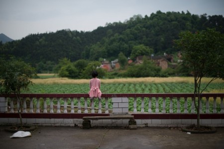 Девочка сидит на ограде в деревне Чжуаншуцзуй провинции Хунань, 30 апреля 2013 года. Фото: Ed Jones/AFP/Getty Images Девочка сидит на ограде в деревне Чжуаншуцзуй провинции Хунань, 30 апреля 2013 года. Фото: Ed Jones/AFP/Getty Images
