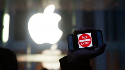 Протестующий держит iPhone с надписью «Вход запрещен» возле магазина Apple на 5-й авеню в Нью-Йорке 23 февраля. Хотя Apple утверждает, что поддерживает конфиденциальность пользователей в США, она тесно сотрудничает с властями Китая. . (Брайан Томас / Getty Images)