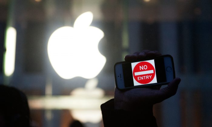 Ступая по тонкому льду: сотрудничество Apple с китайскими властями Протестующий держит iPhone с надписью «Вход запрещен» возле магазина Apple на 5-й авеню в Нью-Йорке 23 февраля. Хотя Apple утверждает, что поддерживает конфиденциальность пользователей в США, она тесно сотрудничает с властями Китая. . (Брайан Томас / Getty Images)