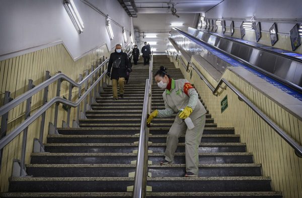 Уханьский коронавирус. Работница дезинфицирует перила в вечерний час пик в Пекине