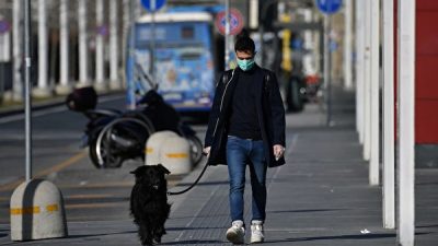 Человек в защитной маске выгуливает собаку в Турине, 10 марта 2020 года, Италия MARCO BERTORELLO/AFP via Getty Images