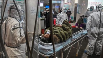 Медицинский персонал в защитной одежде прибыл с пациентом в больницу Красного Креста в Ухане, Китай, 25 января 2020 года. HECTOR RETAMAL/AFP via Getty Images