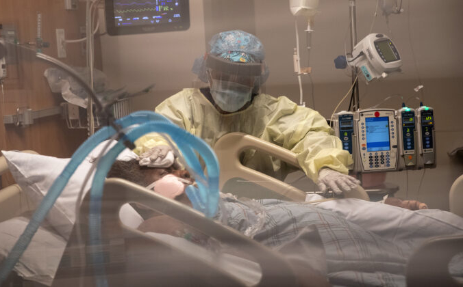 Врач в маске склонилась над больным. John Moore/Getty Images | Epoch Times Россия