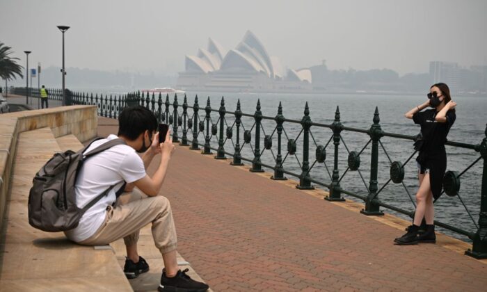 Туристы в масках фотографируются на фоне Оперного театра, окутанного дымом из-за близлежащих лесных пожаров в Сиднее Туристы в масках фотографируются на фоне Оперного театра, окутанного дымом из-за близлежащих лесных пожаров в Сиднее