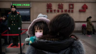 Девочка в маске на центральном вокзале Пекина. Kevin Frayer/Getty Images