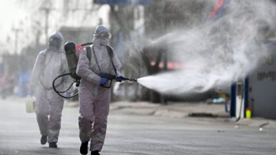 Сотрудники в защитных костюмах распыляют дезинфицирующее средство на улице в районе Гаочэн, который был объявлен зоной высокого риска из-за COVID-19, Шицзячжуан, провинция Хэбэй на севере Китая, 15 января 2021 года. STR/CNS/AFP via Getty Images