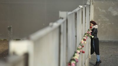 Женщина возлагает цветы на руины Берлинской стены 9 ноября 2015 года, в день 26-й годовщины её сноса. С 1961 по 1989 г. стена отделяла немцев на восточной территории от демократического Запада. Берлинская стена стала символом «холодной войны» и советского коммунизма. Фото: Sean Gallup/Getty Images
