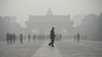 Пожилой мужчина идет перед группой людей во время сильного смога. 20 декабря 2016 год, Пекин. Фото / Wang Zhao/AFP/Getty Images
