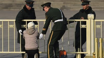 Военизированная полиция останавливает женщину, которая протестует на коленях у Дома народных собраний в Пекине 13 марта 2015 г. Фото: GREG BAKER/AFP/Getty Images