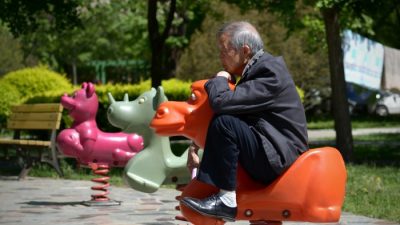 Пожилой мужчина сидит на лошадке в жилом районе Пекина 4 мая 2015 г. (WANG ZHAO / AFP / Getty Images)