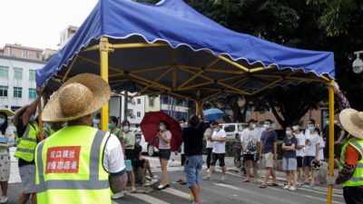 Добровольцы устанавливают палатку, пока жители готовятся к сдаче тестов на COVID-19 в Гуанчжоу в южной китайской провинции Гуандун. 30 мая 2021 г. STR/AFP via Getty Images