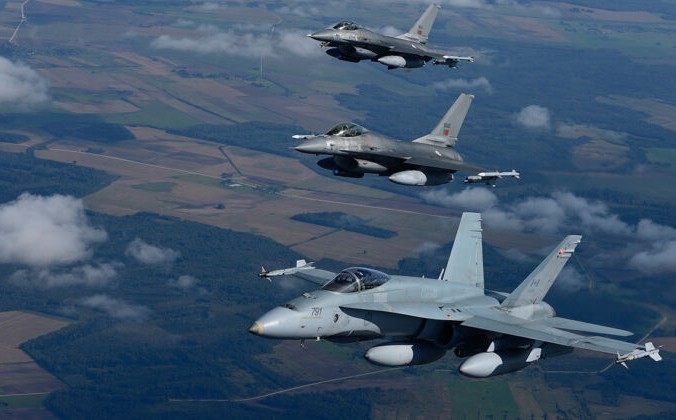 CF-18 Hornet Оперативного воздушного флота Канады летит рядом с двумя португальскими истребителями F-16 Fighting Falcon над Литвой в рамках миссии НАТО по охране воздушного пространства Балтийского моря 15 сентября 2014 г. Canadian Armed Forces | Epoch Times Россия