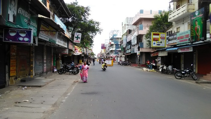 Женщина в маске и сари идёт по пустой улице