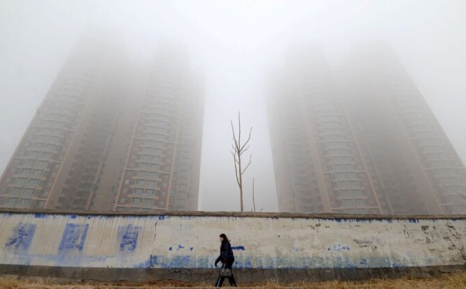 Женщина в маске проходит мимо зданий в Ханьдане, провинция Хэбэй, Китай, 12 января 2019 г. Stringer/Reuters | Epoch Times Россия
