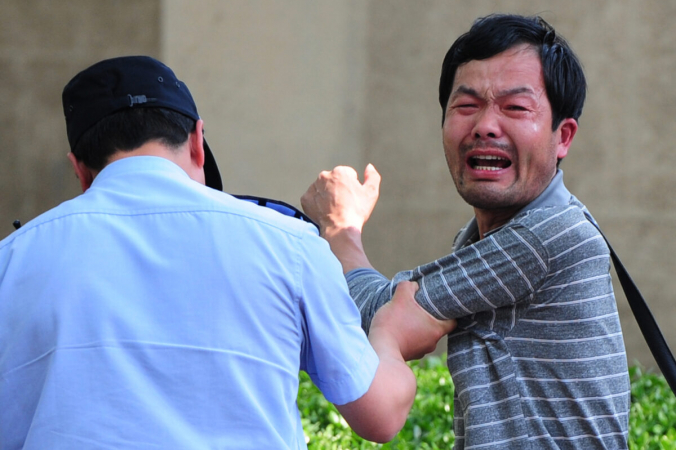 Полицейский задерживает петиционера, который протестует по поводу медицинских проблем и проблем с захватом земли, возле больницы Чаоян в Пекине, Китай, 8 мая 2012 г. (Mark Ralston / AFP / Getty Images) | Epoch Times Россия