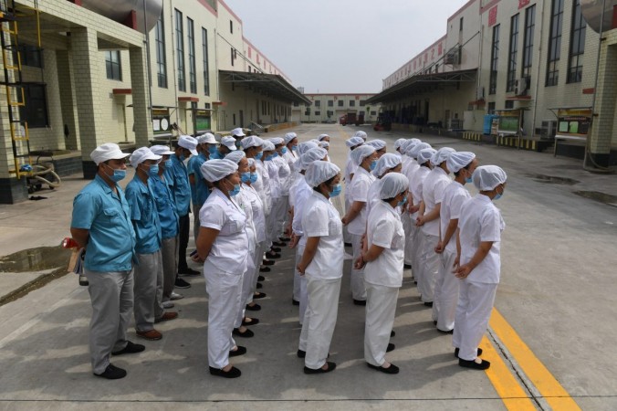 Рабочие выстроились в очередь, чтобы петь коммунистические «красные» песни на фабрике по производству лапши быстрого приготовления, недалеко от деревни в центральной китайской провинции Хэнань, 29 сентября 2017 года. (Грег Бейкер / AFP / Getty Images) | Epoch Times Россия