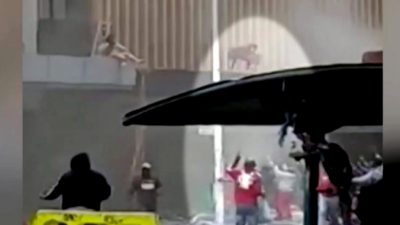 На этом кадре из видео мать бросает ребёнка в толпу на улице в Дурбане, Южная Африка, 13 июля 2021 года (Reuters/Screenshot via NTD)