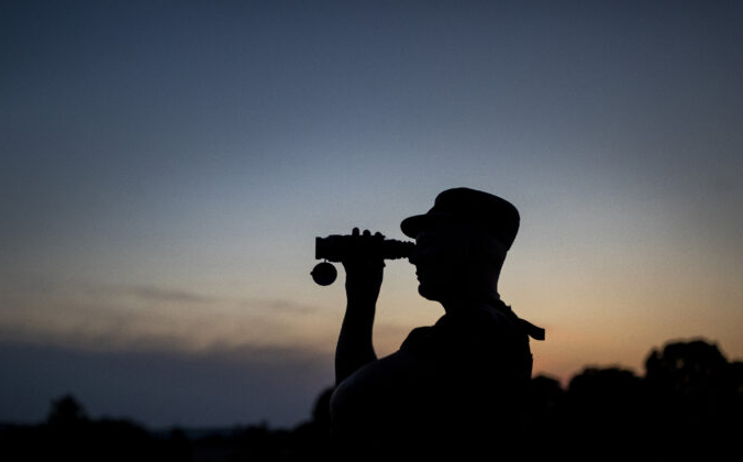 Сотрудник Государственной пограничной службы Литвы смотрит в бинокль во время патрулирования на границе с Беларусью, недалеко от села Пурвенай, Литва, 9 июля 2021 г. Mindaugas Kulbis/AP Photo | Epoch Times Россия