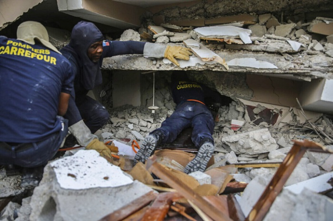 Пожарные ищут выживших внутри разрушенного здания после субботнего землетрясения магнитудой 7,2 в Ле-Ке, Гаити, в воскресенье, 15 августа 2021 г. (AP Photo / Joseph Odelyn) | Epoch Times Россия