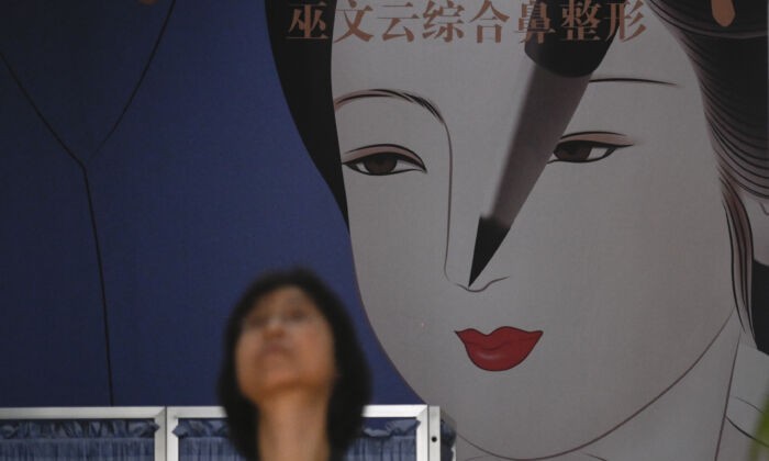 Женщина проходит мимо большого дисплея в клинике пластической хирургии Пекина, 15 июля 2021 года.