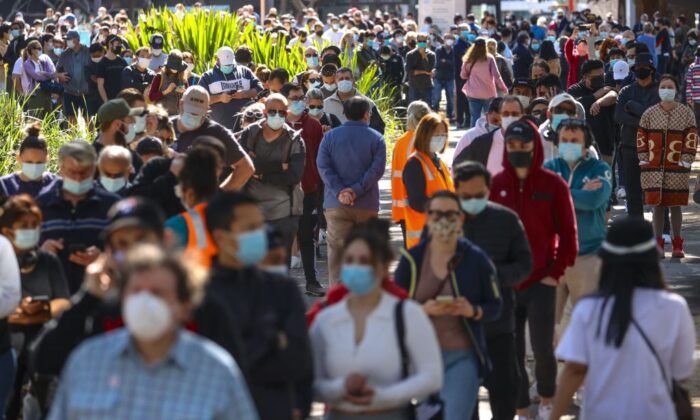 Люди в масках выстраиваются в очередь, ожидая вакцинации в Центре вакцинации Сиднейского олимпийского парка в Хоумбуше в Сиднее, Австралия, 16 августа 2021 г.