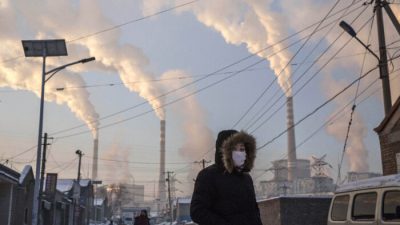 Китаянка в маске идёт неподалёку от угольной электростанции в Шаньси, Китай, 26 ноября 2015 г. Kevin Frayer / Getty Images