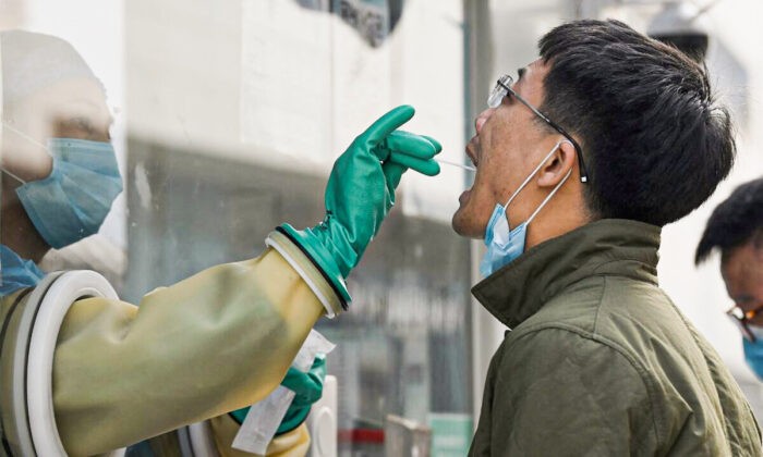 Медицинский работник берёт мазок на COVID-19 на станции тестирования в Пекине, Китай, 25 октября 2021 г. (Noel Celis/AFP via Getty Images) | Epoch Times Россия