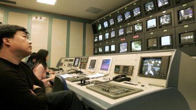 Китайские продюсеры и технические специалисты следят за экранами, пока французский диктор передаёт новости в студии Центрального телевидения Китая (CCTV) в Пекине, 25 ноября 2004 года. (GOH CHAI HIN/AFP/Getty Images)