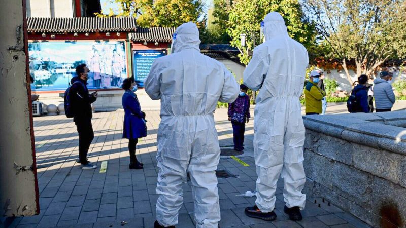 Медицинские работники наблюдают за людьми, стоящими в очереди на сдачу мазков на COVID-19 на станции сбора нуклеиновых кислот в Пекине 26 октября 2021 г. Фото: Noel Celis/AFP via Getty Images
