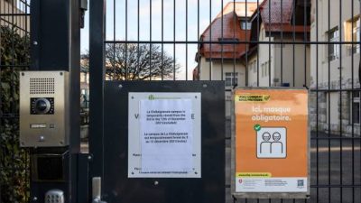 плакат у входа в кампус Шатеньере Международной школы Женевы, закрытый после того, как были обнаружены два ящика варианта Омикрон, в Фунексе, Швейцария. Фото: FABRICE COFFRINI/AFP via Getty Images)