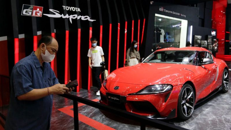 Люди стоят возле автомобиля Toyota GR Supra на международном автосалоне Индонезии в Тангеранге, недалеко от Джакарты, Индонезия, 12 ноября 2021 года. (Ajeng Dinar Ulfiana/Reuters) 