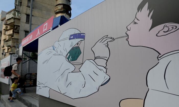 Мужчина с ребёнком входят в центр тестирования на COVID-19 в Шэньчжэне, юго-восточный Китай, 26 сентября 2021 года. Фото: NOEL CELIS/AFP via Getty Images  | Epoch Times Россия