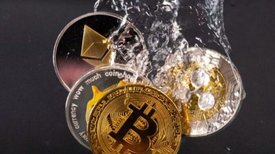 Сувенирные жетоны, представляющие криптовалютные сети Bitcoin, Ethereum, Dogecoin и Ripple, погружаются в воду 17 мая 2022 года. Фото: Dado Ruvic/Illustration/Reuters