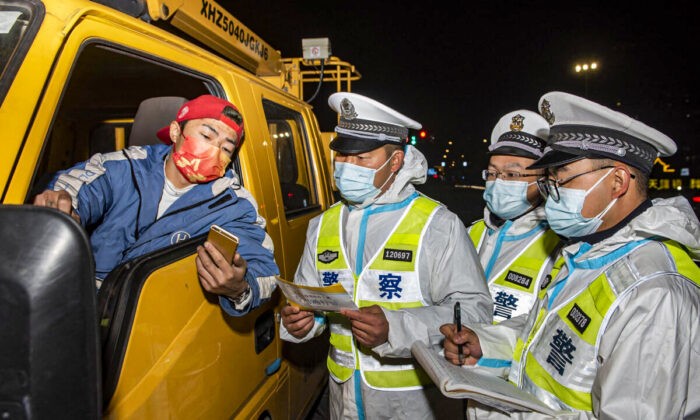 Полицейские проверяют документы у водителя грузовика (слева) на контрольно-пропускном пункте в Нинбо в провинции Чжэцзян на востоке Китая, 18 декабря 2021 г. STR/AFP via Getty Images | Epoch Times Россия