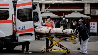 Водители скорой помощи выгружают пациента возле клиники, где лечат пациентов с COVID-19 в Пекине, 21 декабря 2022 года. (Kevin Frayer/Getty Images)